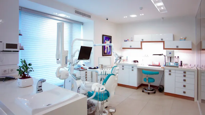 Modern dental treatment room with a patient chair, examination light and clinical equipment.